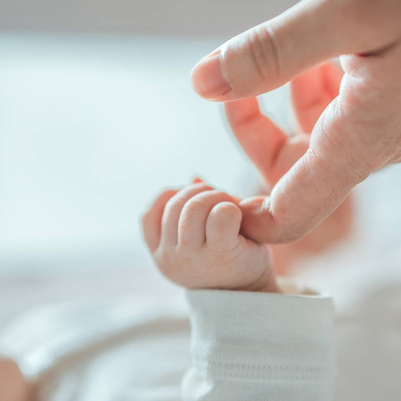 Newborn baby holding parent's finger
